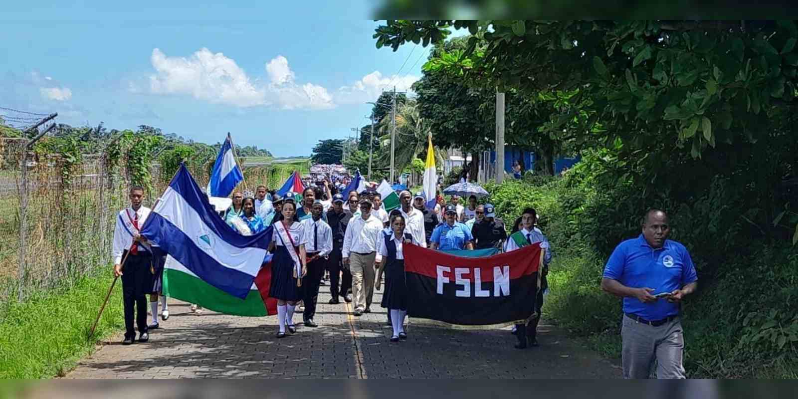 Estudiantes de Corn Islan desfilan con banderas del  partido gobernante.
