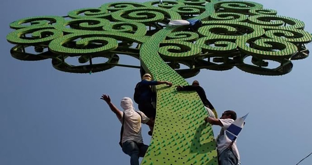 Manifestantes protestan contra Ortega y Murillo escalando un árbol de
hojalata en 2018.